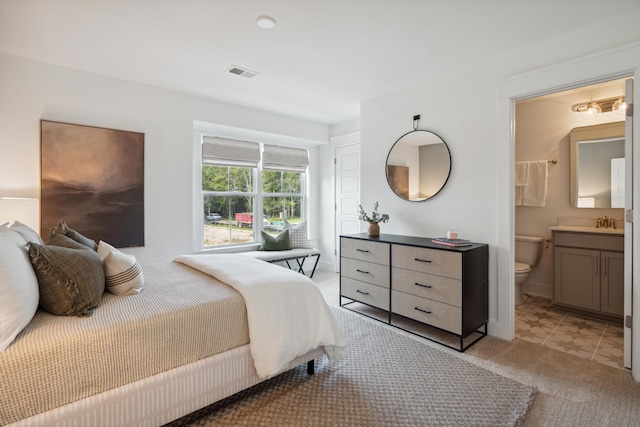 bedroom featuring a sink, visible vents, ensuite bathroom, and light carpet