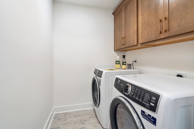 clothes washing area featuring washer and dryer, baseboards, and cabinet space