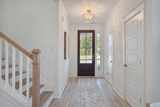 foyer entrance with light wood-type flooring, stairway, visible vents, and a chandelier