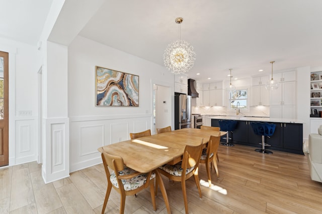 dining room with sink, light hardwood / wood-style flooring, and a chandelier