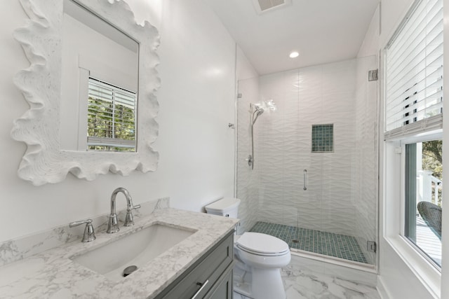 bathroom featuring toilet, vanity, and a shower with shower door