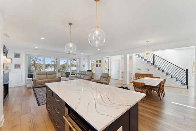 kitchen with pendant lighting, light stone counters, and light hardwood / wood-style flooring