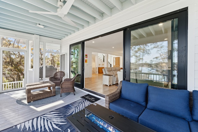 sunroom / solarium featuring beamed ceiling and ceiling fan