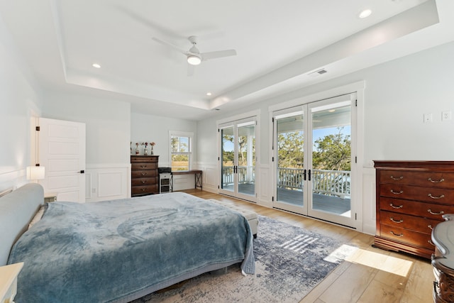 bedroom with french doors, a tray ceiling, access to exterior, and light wood-type flooring