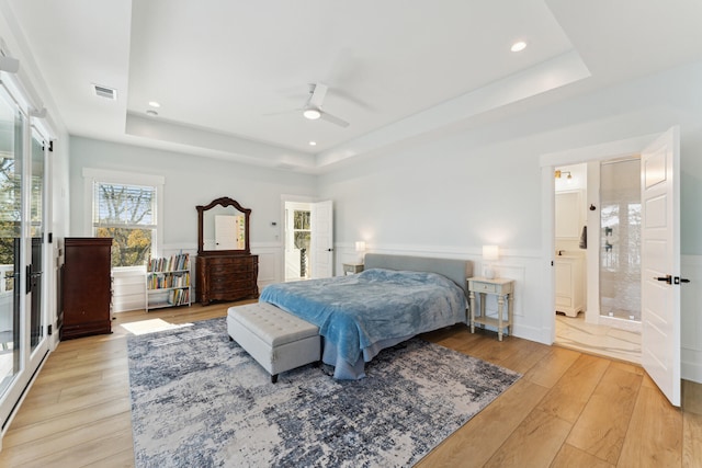 bedroom featuring a raised ceiling, ceiling fan, and light hardwood / wood-style flooring