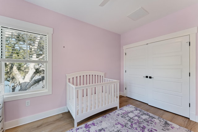 bedroom featuring hardwood / wood-style flooring, a closet, and a crib