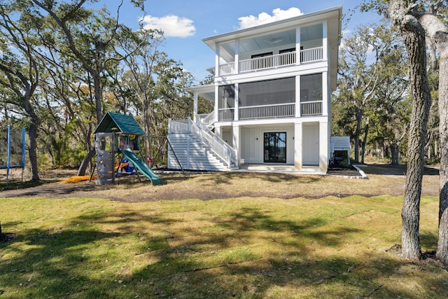 back of house featuring a playground, a sunroom, and a yard