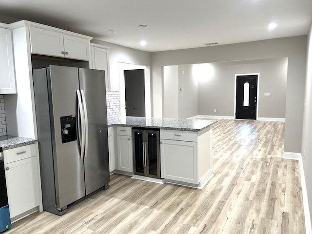 kitchen featuring white cabinets, light stone countertops, wine cooler, and stainless steel fridge