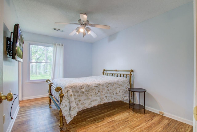 bedroom with ceiling fan, a textured ceiling, and hardwood / wood-style flooring