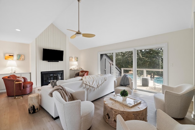 living room featuring a large fireplace, high vaulted ceiling, light wood-style flooring, and recessed lighting