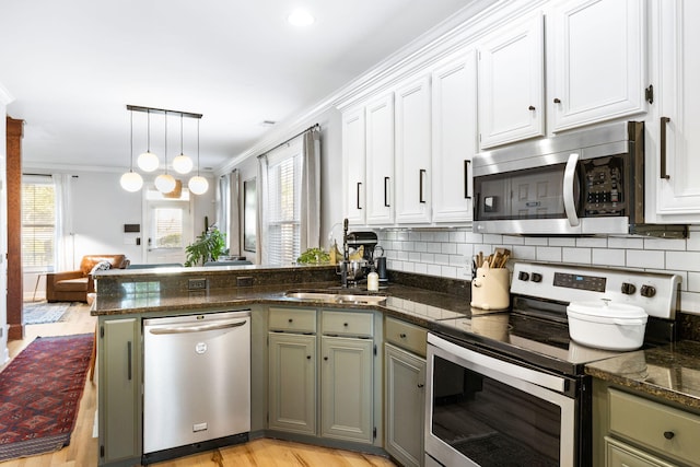 kitchen featuring crown molding, hanging light fixtures, appliances with stainless steel finishes, sink, and white cabinets