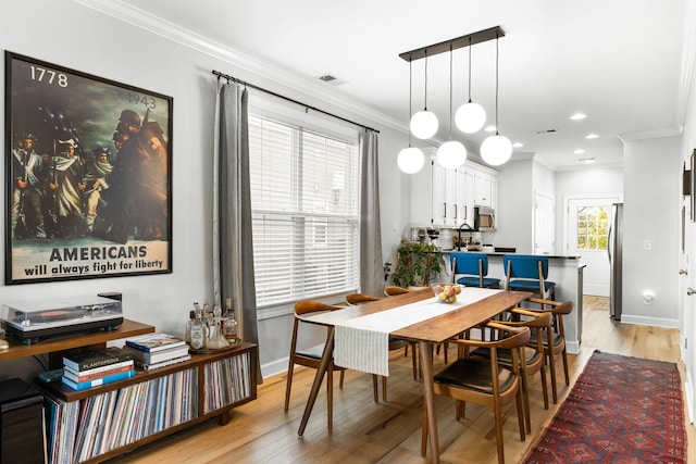 dining area featuring crown molding and light wood-type flooring