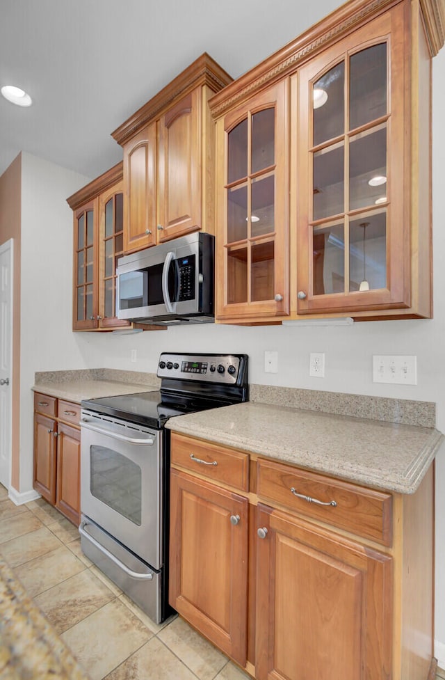 kitchen featuring appliances with stainless steel finishes, light stone countertops, and light tile floors