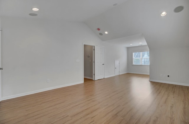 additional living space with light hardwood / wood-style flooring and lofted ceiling