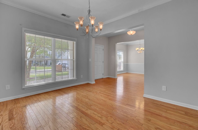 empty room with a notable chandelier, ornamental molding, and light hardwood / wood-style flooring