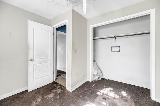 unfurnished bedroom with a closet, a textured ceiling, and dark colored carpet