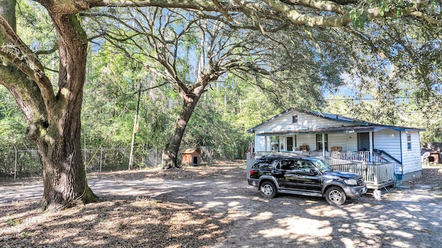 view of front of home featuring a porch, solar panels, and a shed