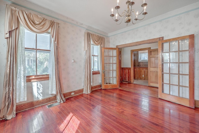 unfurnished room with hardwood / wood-style floors, french doors, and a notable chandelier