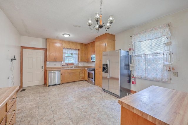 kitchen featuring light tile patterned floors, sink, a notable chandelier, a textured ceiling, and stainless steel appliances