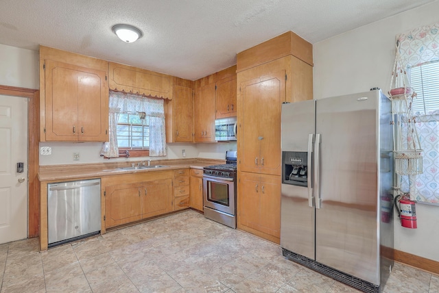 kitchen with appliances with stainless steel finishes, sink, and a textured ceiling