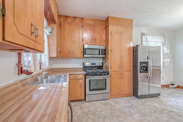 kitchen featuring sink, stainless steel appliances, a textured ceiling, and a healthy amount of sunlight