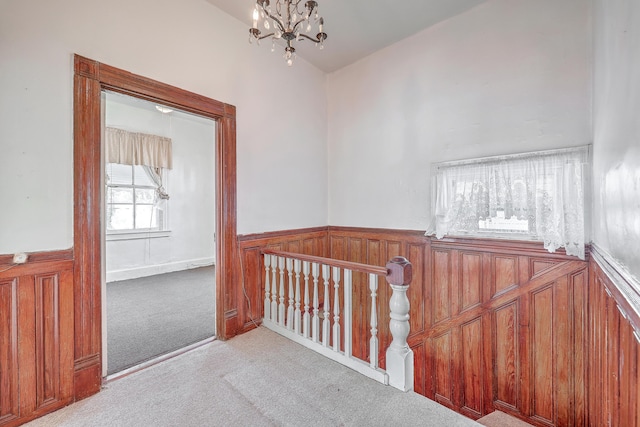 hall featuring light carpet and a notable chandelier