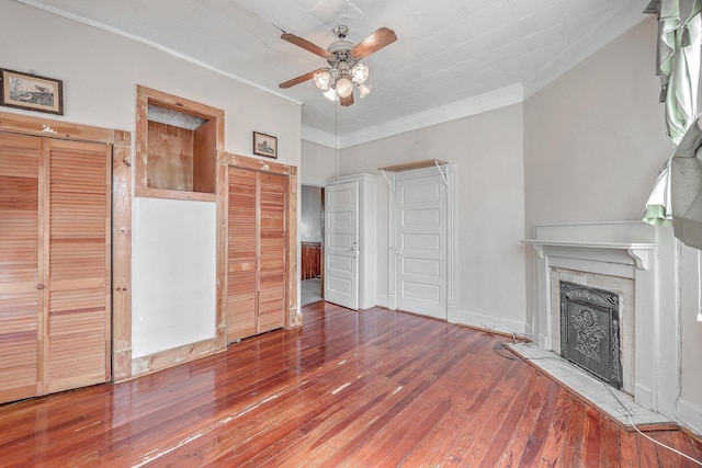 unfurnished living room with ornamental molding, a brick fireplace, hardwood / wood-style floors, and ceiling fan