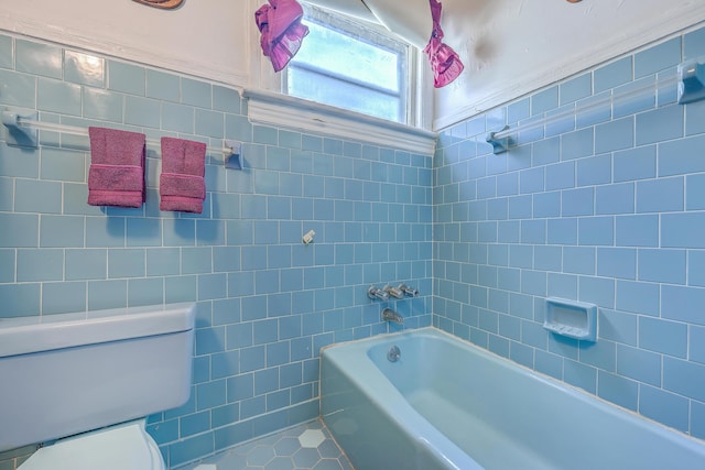 bathroom with tile patterned flooring, tile walls, toilet, and washtub / shower combination