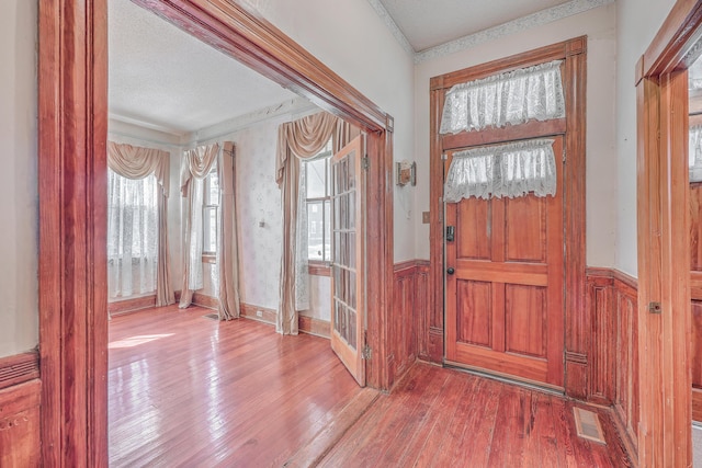 entryway featuring a textured ceiling, hardwood / wood-style floors, and crown molding