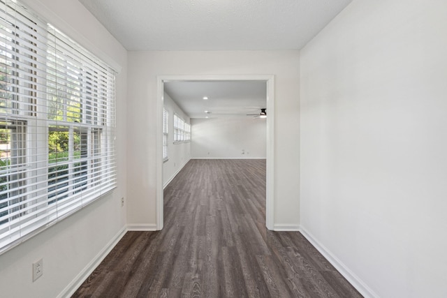 corridor with baseboards and wood finished floors