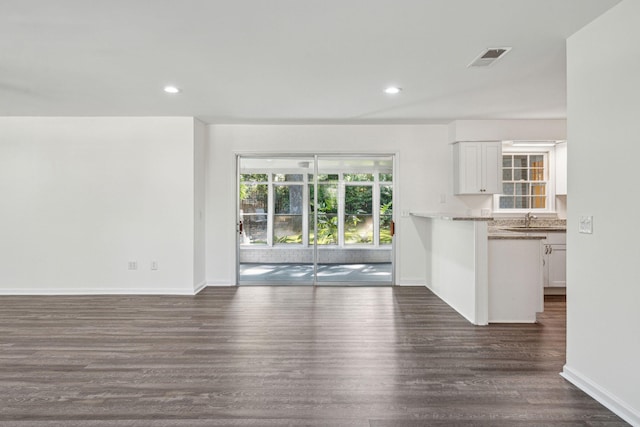 unfurnished living room featuring visible vents, a sink, baseboards, recessed lighting, and dark wood-type flooring