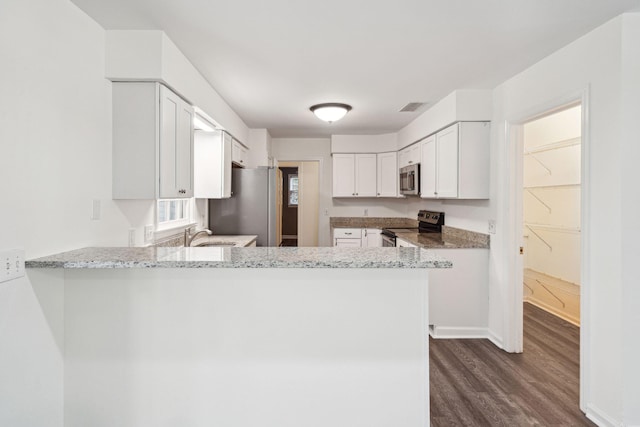 kitchen with stainless steel appliances, white cabinetry, a peninsula, visible vents, and dark wood-style floors