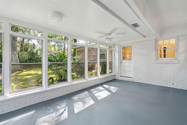 unfurnished sunroom with visible vents, a ceiling fan, plenty of natural light, and brick wall