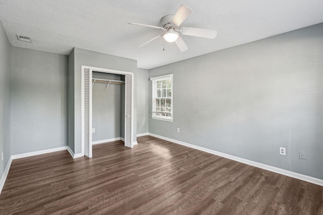 unfurnished bedroom with visible vents, dark wood-style flooring, baseboards, and a closet