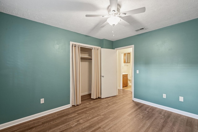 unfurnished bedroom featuring visible vents, baseboards, a textured ceiling, and wood finished floors