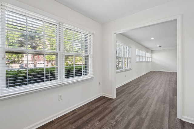empty room with baseboards and dark wood finished floors