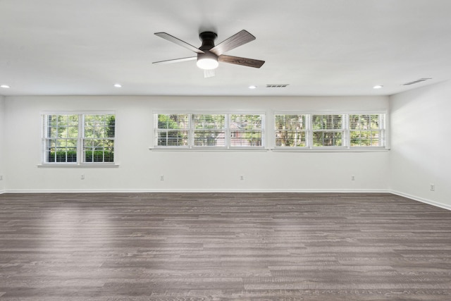 empty room with a healthy amount of sunlight, visible vents, ceiling fan, and dark wood-type flooring