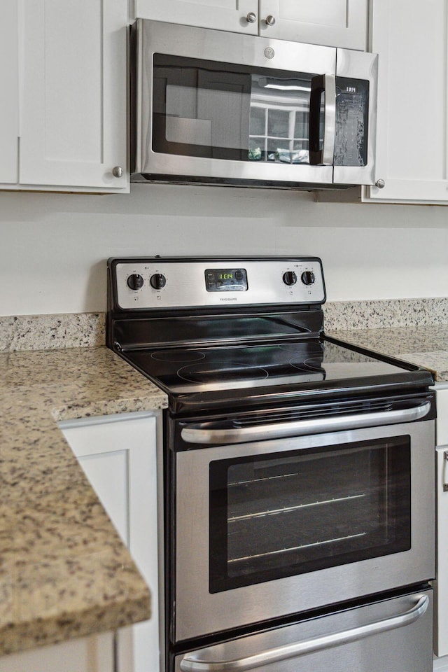 kitchen featuring white cabinets, stainless steel appliances, and light stone countertops
