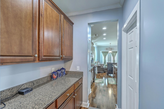 kitchen with stone counters, dark wood-type flooring, brown cabinets, ornamental molding, and recessed lighting