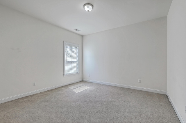 empty room featuring light carpet, baseboards, and visible vents