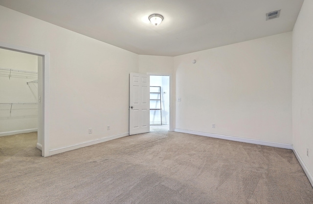 unfurnished bedroom featuring baseboards, visible vents, a spacious closet, and carpet flooring
