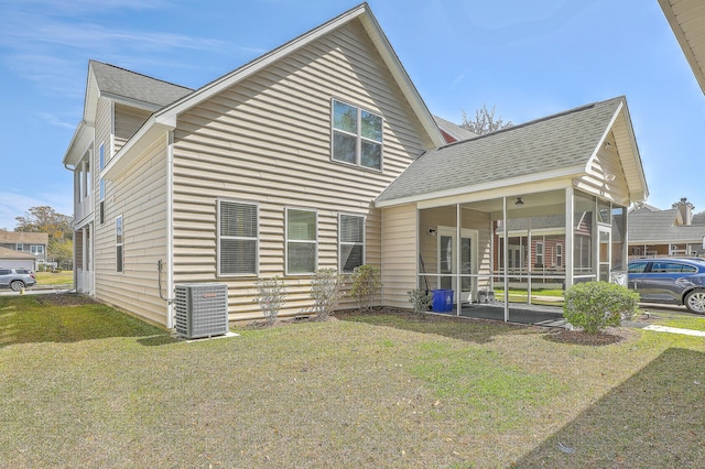 back of house with central AC unit, roof with shingles, a sunroom, and a yard
