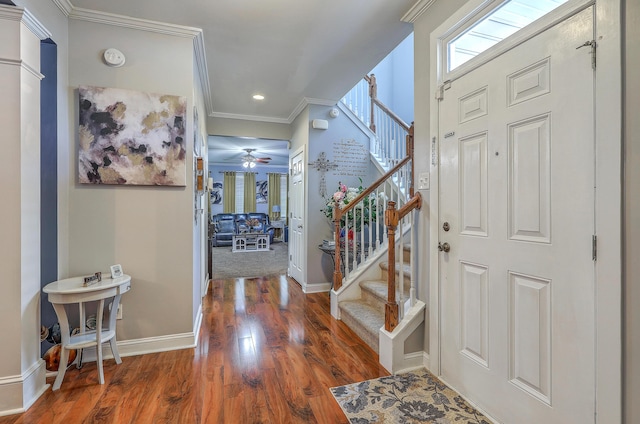 entrance foyer featuring stairs, ornamental molding, baseboards, a ceiling fan, and wood finished floors