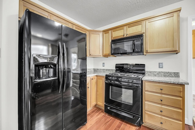 kitchen featuring light brown cabinets, light stone counters, a textured ceiling, black appliances, and light wood-type flooring