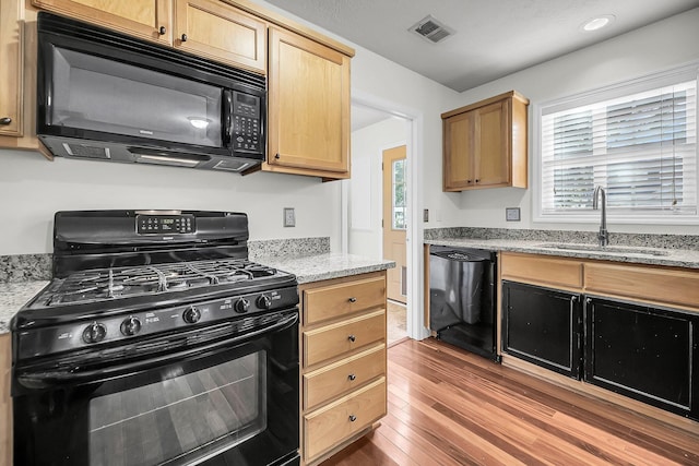 kitchen featuring light stone countertops, sink, black appliances, and dark hardwood / wood-style floors