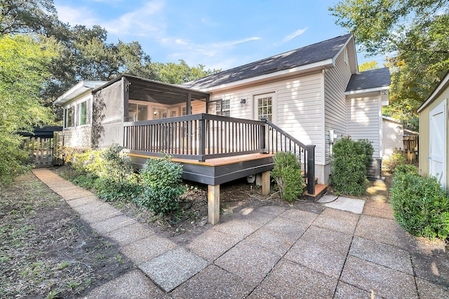 back of property featuring a deck and a sunroom