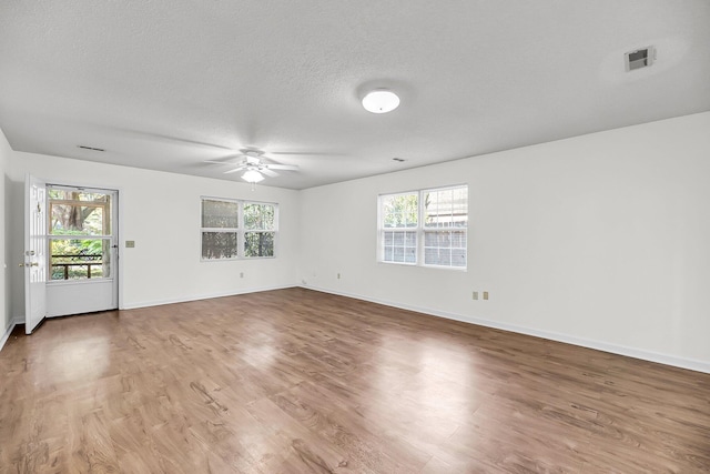 spare room with hardwood / wood-style floors, a healthy amount of sunlight, and a textured ceiling