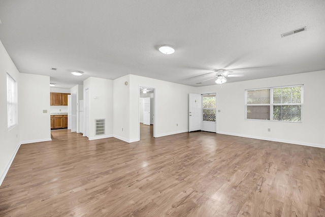 unfurnished living room with hardwood / wood-style floors, a textured ceiling, and ceiling fan