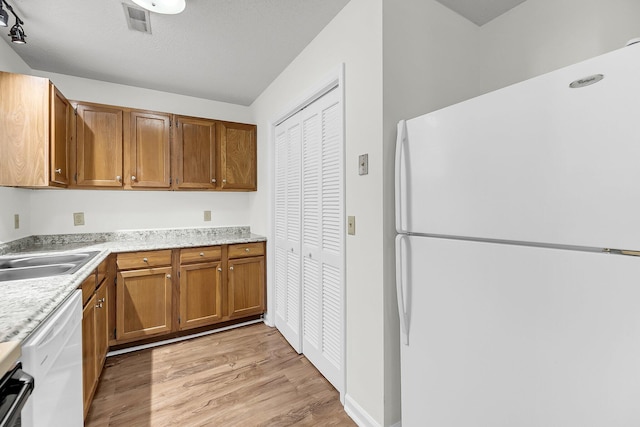 kitchen with a textured ceiling, light hardwood / wood-style flooring, white appliances, and sink