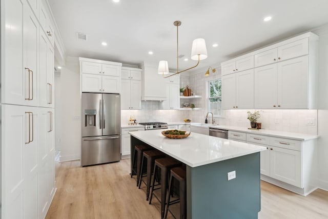 4620 Ohear Ave, North Charleston, SC 29405 - kitchen featuring appliances with stainless steel finishes, a breakfast bar area, light wood finished floors, backsplash, and white cabinets
